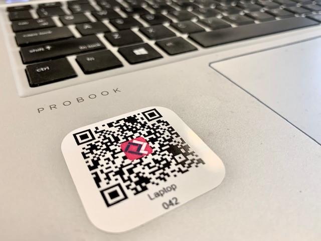 Een QR-code wordt gescand met een smartphone naast een laptop met de QR-Database-omgeving open